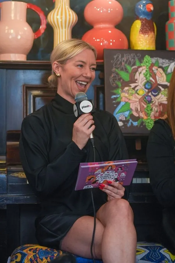 Sophie East, founder of The Women's Circle, laughing while holding a copy of The Women's Circle booklet