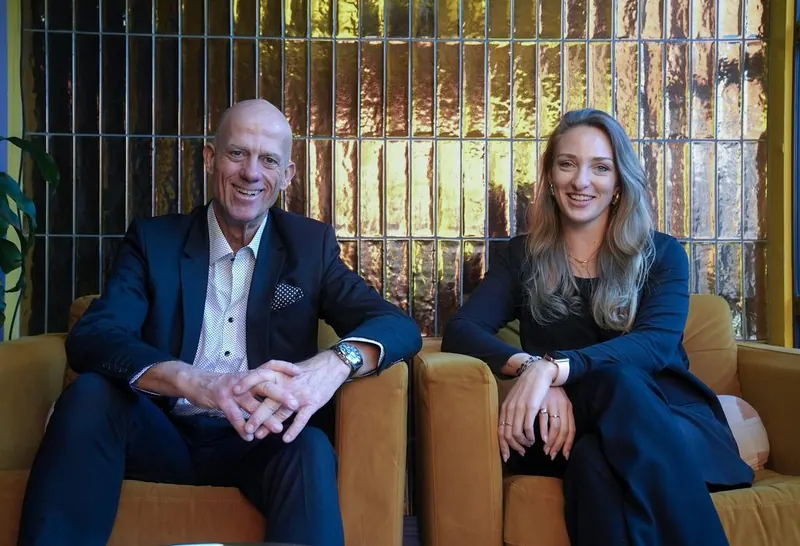 Two Women's Circle guests sitting together on gold armchairs, smiling for the camera