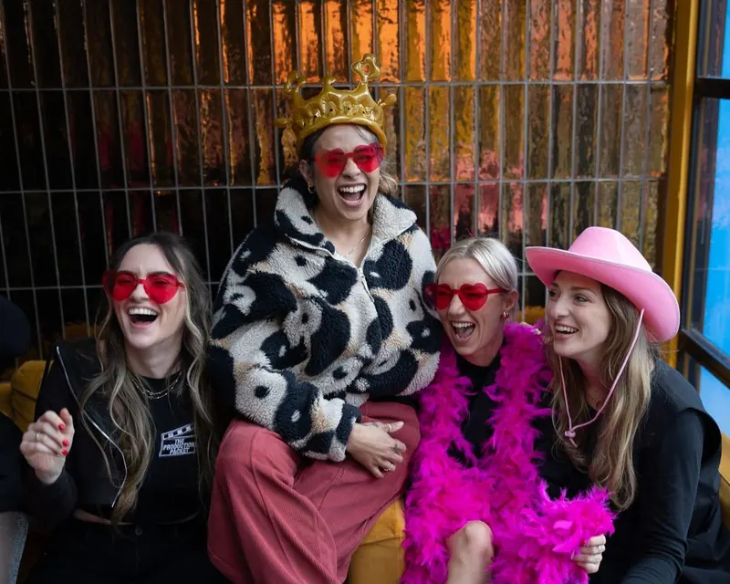 Women's Circle guests laughing together wearing heart glasses and a party crown