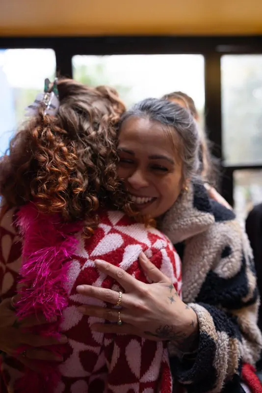 Two Women's Circle guests sharing a warm hug indoors