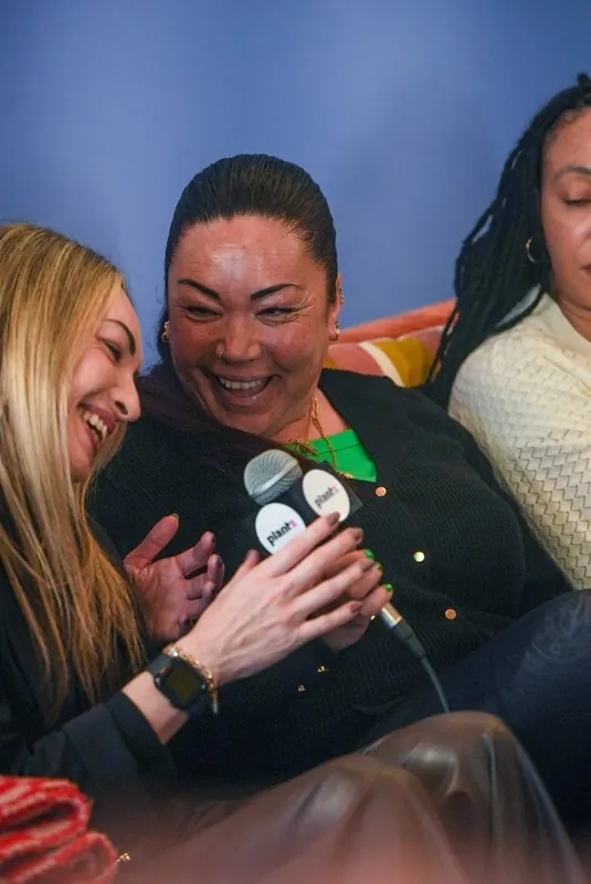 A Women's Circle guest laughing while holding a Plantz branded microphone during an interview