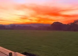A vivid orange and pink sunset over open fields at the venue