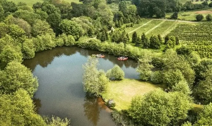 Aerial view of a wild swimming lake surrounded by trees, with two kayaks on the water